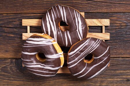 Three donuts with chocolate on dark wooden tabled, top viewの写真素材