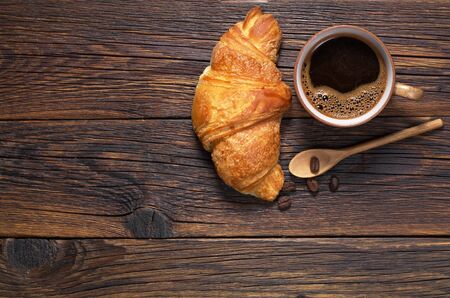 Cup of hot coffee and croissant on dark wooden table, top view. Space for textの写真素材