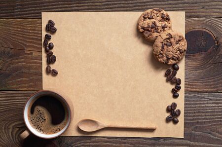 Coffee with chocolate cookies and brown blank paper for text on dark wooden background, top viewの写真素材