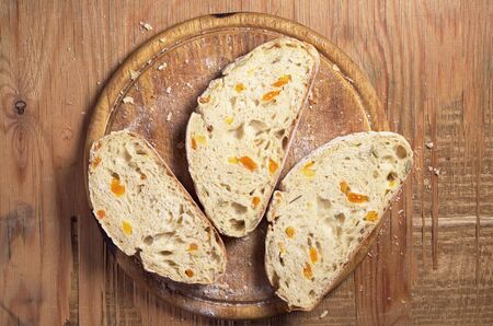 Sliced ciabatta bread with dried apricot and pumpkin seeds on old wooden table