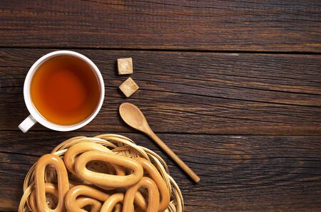 Cup of tea and fresh sweet bagels on dark wooden table, top view. Space for textの写真素材