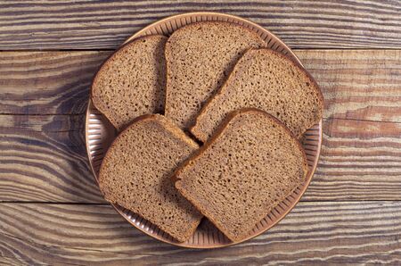 Rye bread slices in plate on wooden table, top viewの写真素材