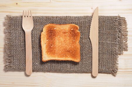 Slice of toasted bread, wooden fork and knife on table, top viewの写真素材
