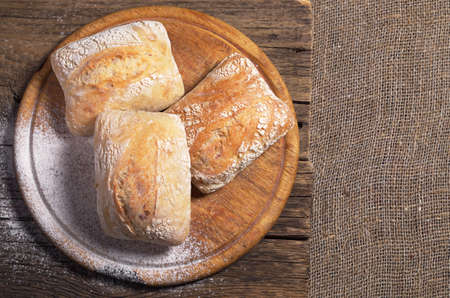 Fresh ciabatta bread on cutting board, top view