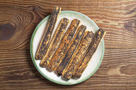 Cookies with poppy seeds in plate on wooden background, top viewの写真素材
