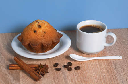 Cup of hot coffee and cupcake with raisins for breakfast on tableの写真素材