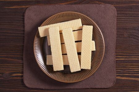 Sweet wafers in plate on brown wooden table, top viewの写真素材