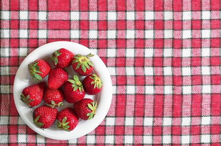 Strawberry in plate on red tablecloth, top view. Space for textの写真素材