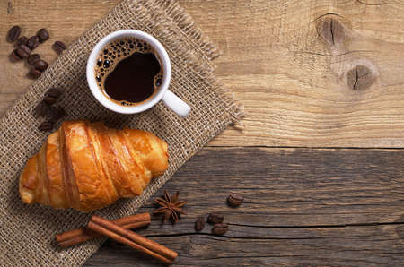 Top view of coffee and fresh croissant on old wooden tableの写真素材