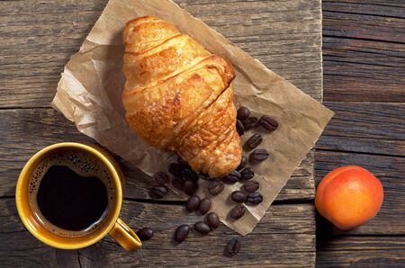 Top view of coffee and fresh croissant for breakfast on old wooden table, top viewの写真素材
