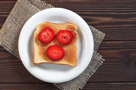 Toast with strawberries in plate on dark wooden table, top viewの写真素材