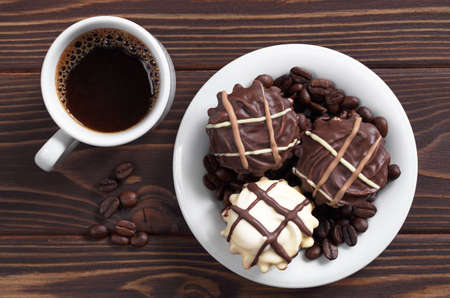 Cup of hot coffee and cookies with white and brown chocolate for breakfast on dark wooden table, top viewの写真素材
