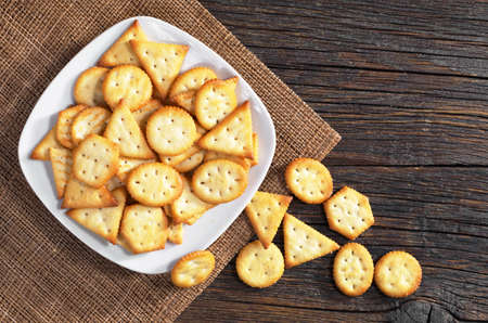 Crackers biscuits with cheese flavor in plate on dark wooden background, top viewの写真素材