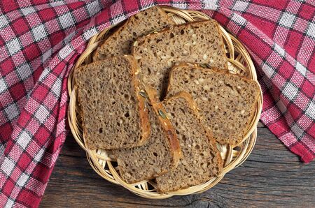 Bread slices with different seeds in wicker plate on wooden table and red tablecloth, top viewの写真素材