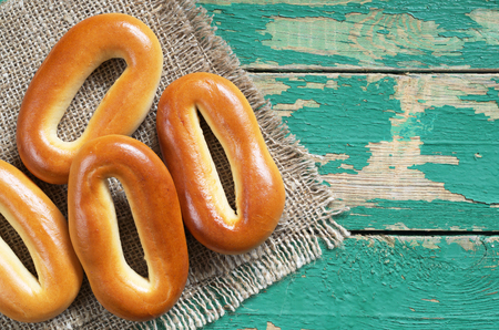Oval bagels - sweet bread roll on old green wooden background, top view. Space for textの写真素材