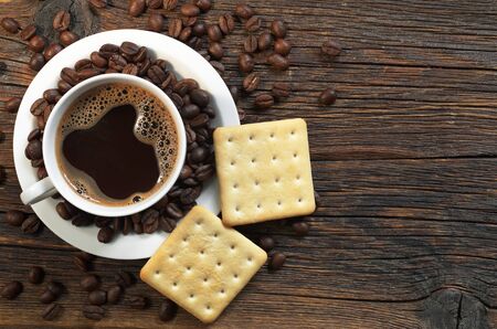 Cup of hot coffee and crackers for breakfast on dark wooden table, top viewの写真素材