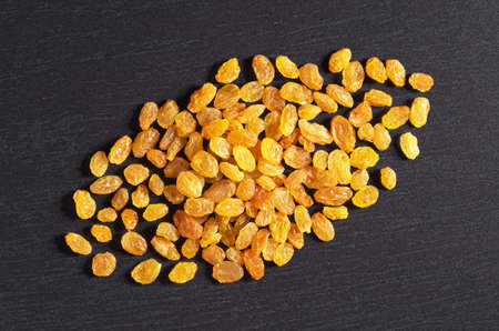 Pile of raisins on black stone background, top viewの写真素材