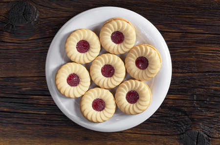 Cookies with raspberry jam and vanilla flavor in plate on dark wooden background, top viewの写真素材