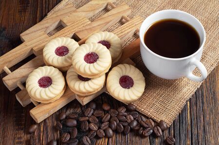 Cup of coffee and cookies with raspberry jam on dark wooden tableの写真素材
