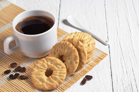 Cup of coffee and sweet round cookies for breakfast on white wooden tableの写真素材