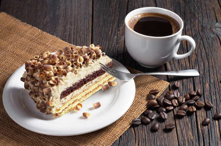 Cup of coffee and slice cream cake with decorated chocolate chips on dark wooden tableの写真素材
