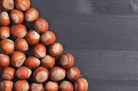 Vegetarian food hazelnuts on black wooden background, top view with space for text