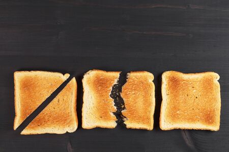 Slices of toast bread whole, cut and broken on black wooden background. Top view with space for textの写真素材