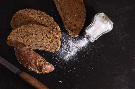 Overhead view of sliced bread with sunflower seeds and salt on old black metal, contrast low lightの写真素材