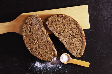 Two slice bread with sunflower seeds and salt on old black metal background, top view. Contrast side lightの写真素材