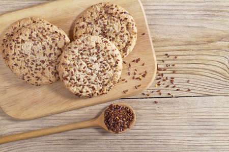 Cookie with flax seeds and sesame on cutting board on wooden table, top view