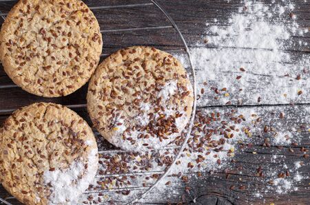 Cookies with flax seeds and sesame on a metal grate against the background of an old wooden surface,...