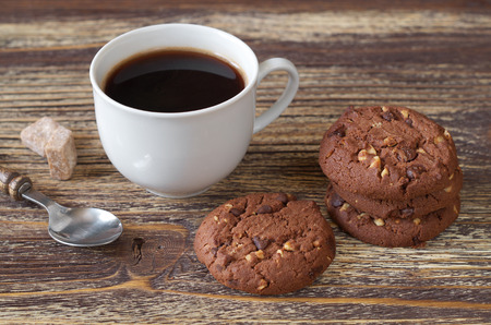 Cup of coffee and chocolate cookies with nuts for breakfast on old wooden tableの写真素材