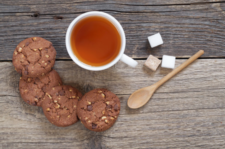 Chocolate cookies with nuts and cup of tea on the old wooden table, top viewの写真素材