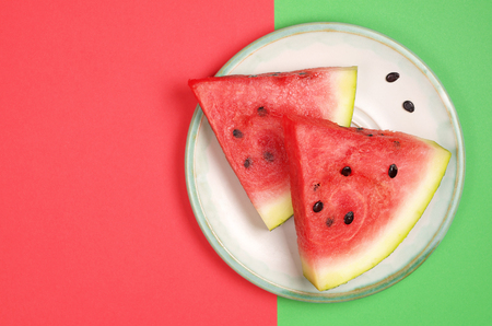 Watermelon slices in plate on red and green background, top view with copy spaceの写真素材