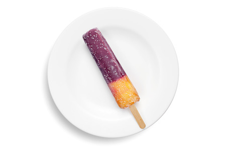 Fruit ice cream on a stick in plate on a white background, top view. Frozen juice blackcurrant and...