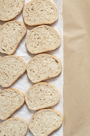 Bread with bran is located in white crumpled paper as a background view from above. Space for textの写真素材