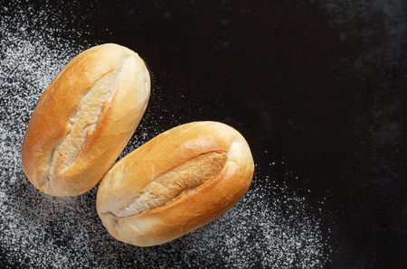Loaves of small wheat bread on old black metal background, top view with copy spaceの写真素材