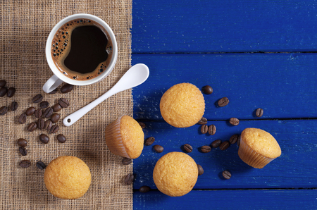 Delicious mini muffins and cup of coffee on blue wooden table, top viewの写真素材
