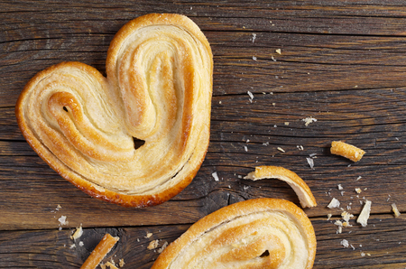 Palmier biscuits - french puff pastry cookies whole and broken on an old wooden background, top viewの写真素材
