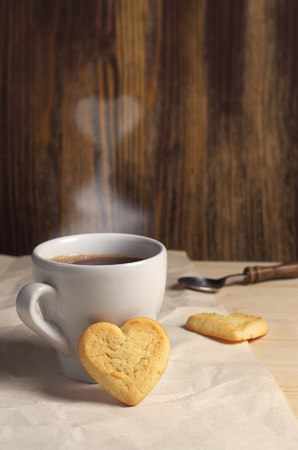 Cookies in the shape of a heart  and cup of coffee on wooden tableの写真素材