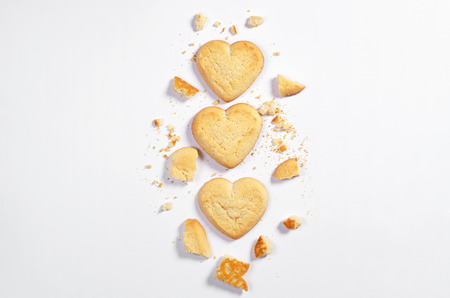 Shortbread cookies in shape of heart whole end broken on white background, top view with space for textの写真素材