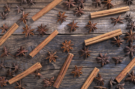 Background from cinnamon sticks and anise stars on old wood, top viewの写真素材