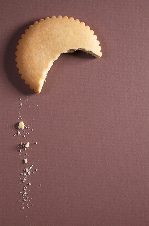 Piece of gingerbread in the form of the crescent and crumbs on a brown background. Top view with space for textの写真素材