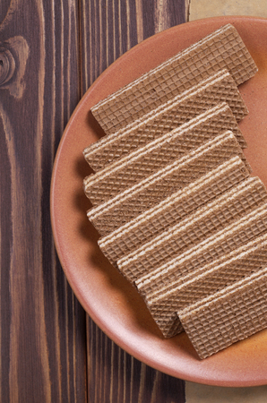 Chocolate wafers in plate on brown wooden table close up, view from aboveの写真素材