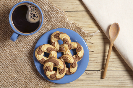 Sweet cookies and coffee in blue dishes on burlap, located on a wooden table, top viewの写真素材