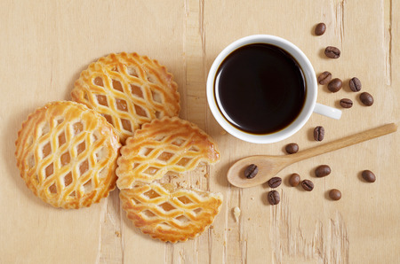 Lattice topped pastries with an apple filling and cup of coffee on old wooden background, top viewの写真素材