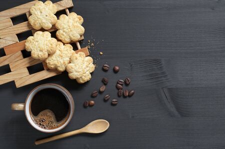 Cup of coffee and biscuits with coconut chips on the background of a black wooden table, top view with space for textの写真素材
