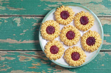 Shortbread cookies with cherry marmalade in plate on old green wooden background, top viewの写真素材