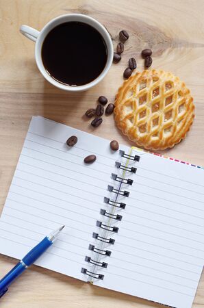 Notebook, coffee and cakes with apple filling on old wooden background, top view with copy spaceの写真素材