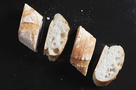 From above pieces of fresh bread arranged in line against black metal backgroundの写真素材